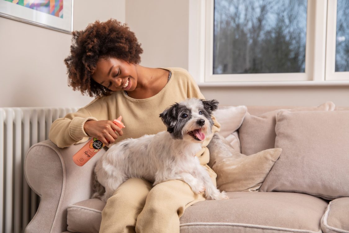 smiling woman spraying her Terrier with Quick Fix spray