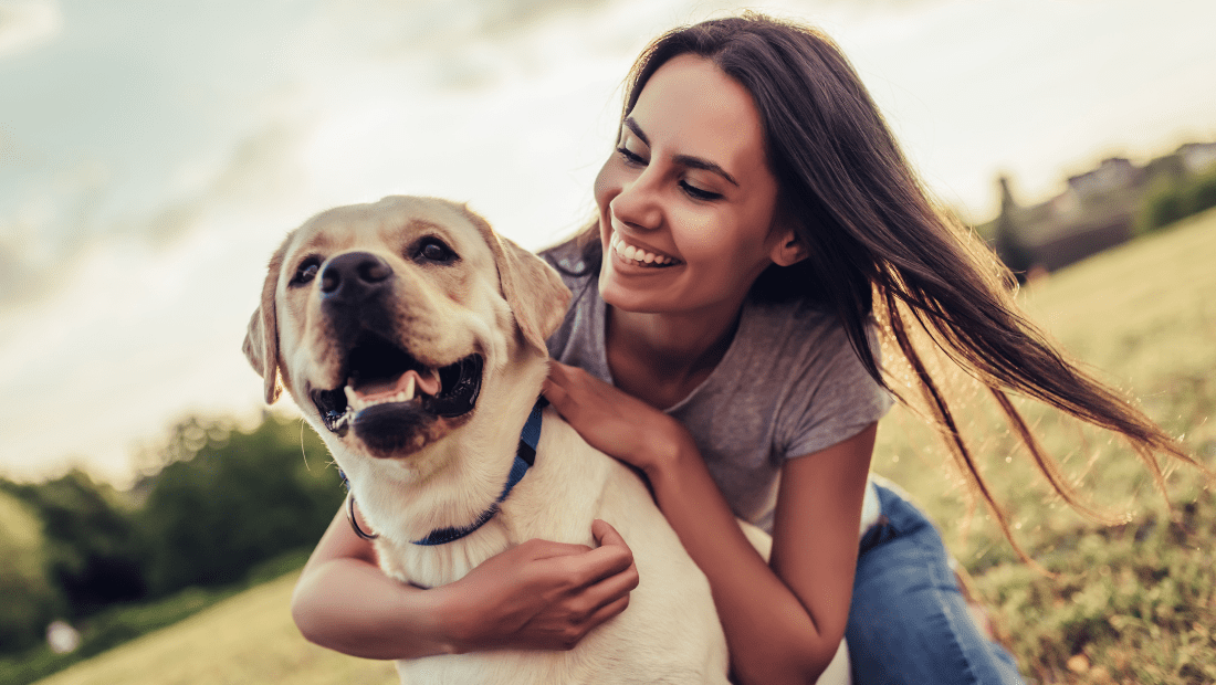 A happy woman and a happy dog in a field