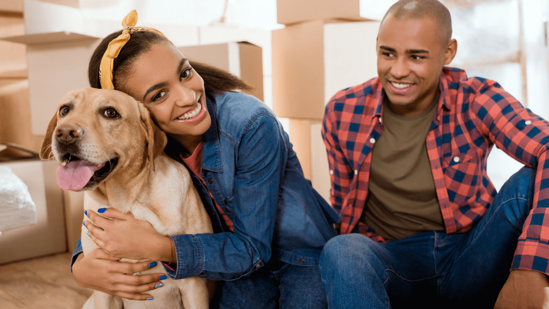 A couple hugging their Labrador as they moving house